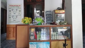 Bancada de recepção com quadro de cardápio, geladeira e exposição de água e bebidas engarrafadas.