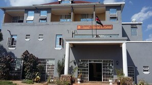 A building with a sign reading 'Treat House Resort,' a flag, and a gated entrance. - Treat House Resort (Kisii)