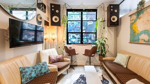 A living room with a sofa, two armchairs, a coffee table, a TV, and a large map on the wall. - Hosier Lane Hideaway Events & City Life (Melbourne)