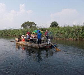 Un grupo de personas en un bote pequeño con un remo, rodeado de agua y vegetación.