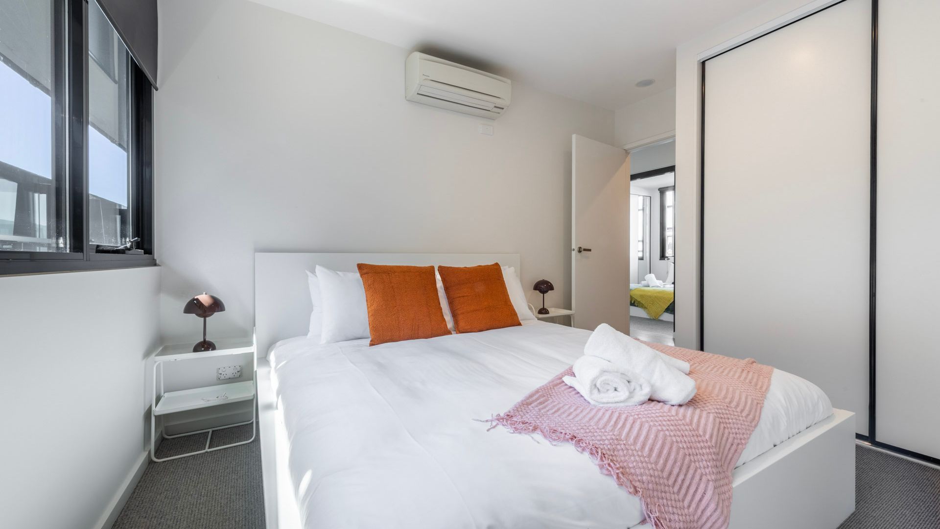 Habitación de hotel con cama, mesita de noche, lámpara, ventana y aire acondicionado.
