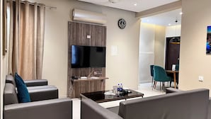 A modern living room with a flat-screen TV, a coffee table, and seating. - Hamsun (Karachi)