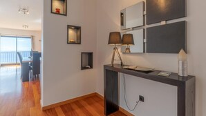 Ein modernes Hotelzimmer mit Holzboden, einem Schreibtisch mit Lampe und einem großen Fenster mit Meerblick.