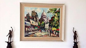 A framed painting of a bustling street scene with buildings and people, displayed above a fireplace with two small statues on either side. - Percy Place (Bath)