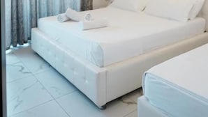 A modern bedroom with a large bed, a bedside table, and a curtain. - Vila Mucodemi (Ksamil)