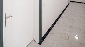 A hallway with white walls, a marble floor, and doors with a number sign. - Vila Mucodemi (Ksamil)