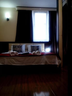 Une chambre d’hôtel avec un lit, des oreillers, une fenêtre et des rideaux.