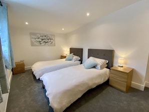 Un dormitorio con dos camas, una obra de arte en la pared y lámparas de noche.