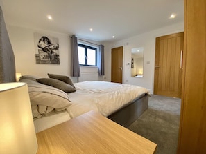Un dormitorio con cama, mesita de noche y ventana con cortinas.