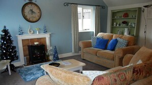 A living room with a fireplace, a sofa, a coffee table, and a Christmas tree. - High Grange Cottages (Bedale)