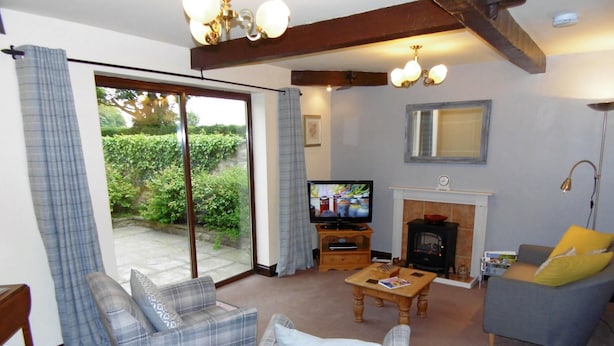 A living room with a television, fireplace, and seating area. - High Grange Cottages (Bedale)