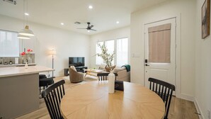 A modern living room with a dining area, a flat-screen TV, and a ceiling fan. - Modern 3BR | 3 Baths | Near NRG & Med Center (Houston)