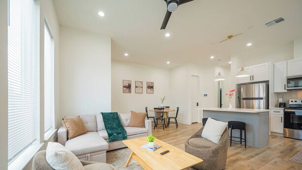 A modern living room with a sofa, armchairs, a coffee table, and a dining area. - Modern 3BR | 3 Baths | Near NRG & Med Center (Houston)