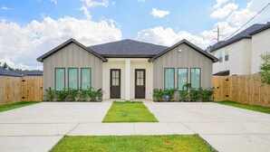 A two-story residential house with a front yard, a driveway, and a wooden fence. - Modern 3BR | 3 Baths | Near NRG & Med Center (Houston)