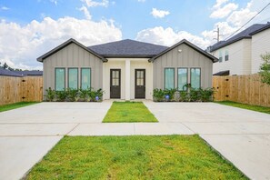 Una casa residencial de dos pisos con un patio delantero, entrada para coches y valla de madera.