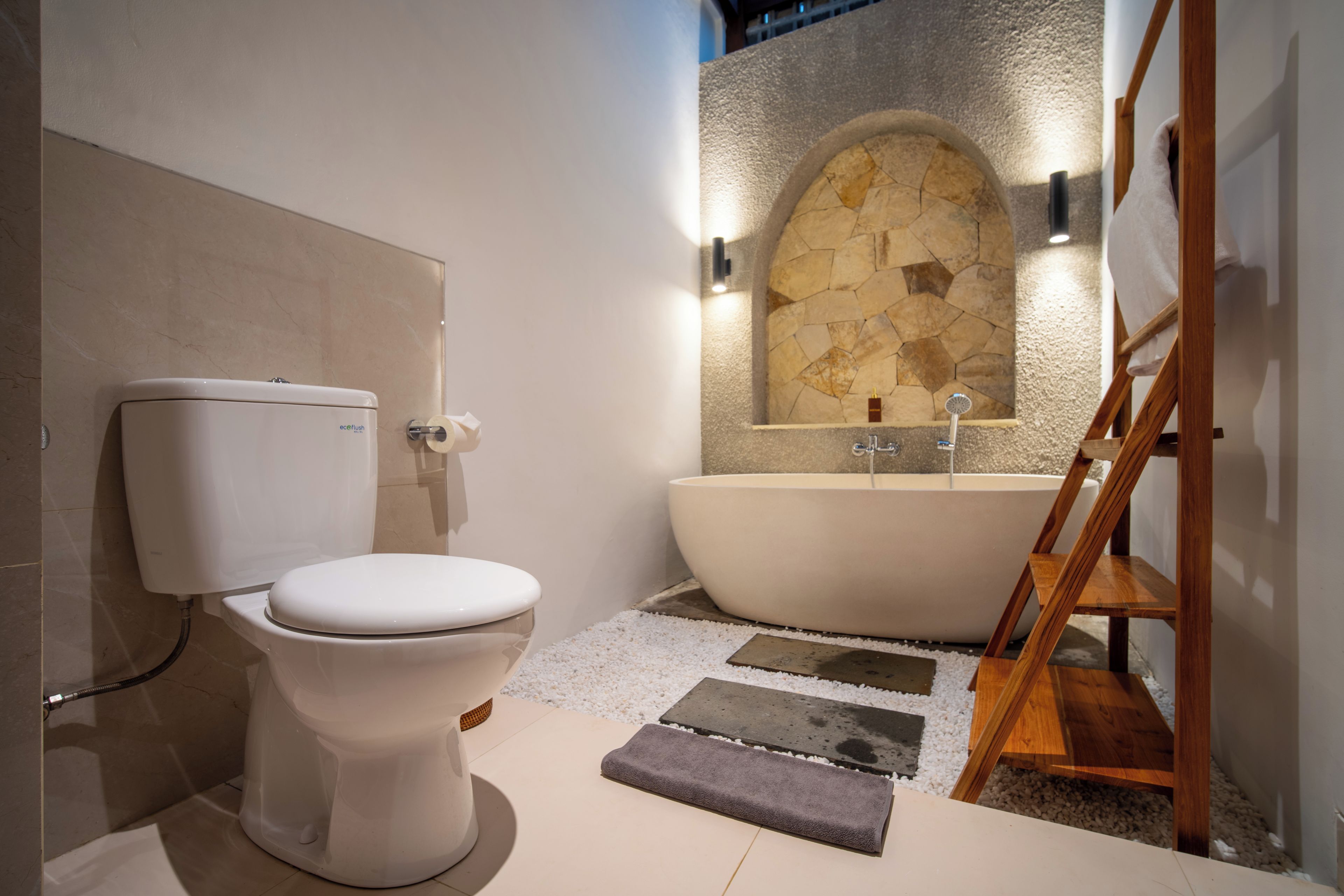 Un baño moderno con inodoro, bañera y pared de piedra.