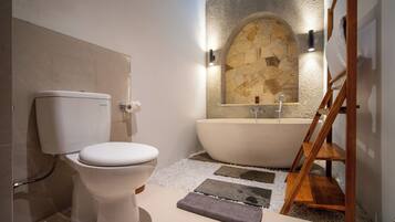Un baño moderno con inodoro, bañera y pared de piedra.