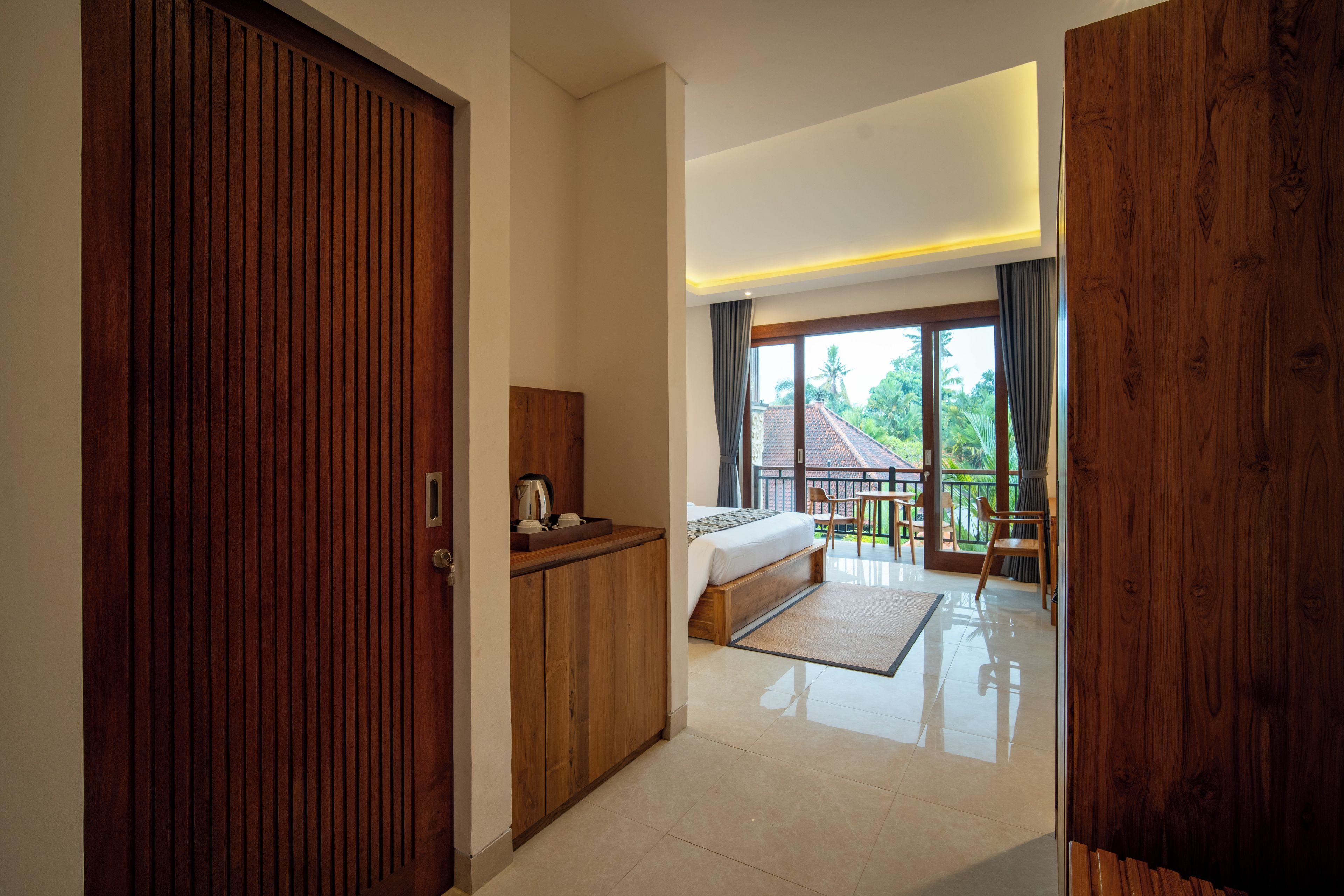 Habitación de hotel con armario de madera, cama, una mesita con hervidor y vistas al exterior.