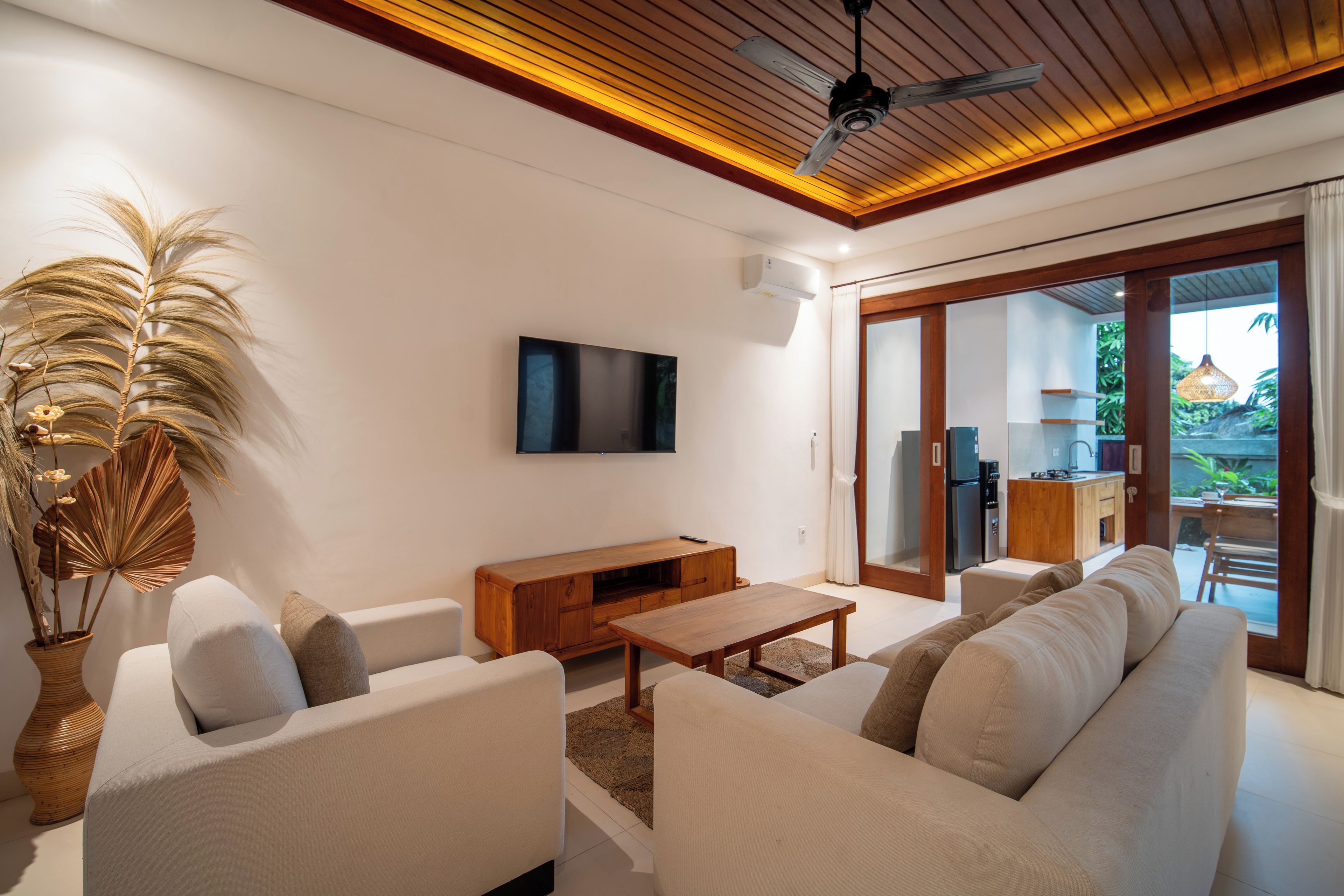 Una sala moderna con un conjunto de sofá, una mesa de centro de madera y un televisor de pantalla plana montado en la pared.