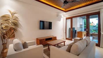 Una sala moderna con un conjunto de sofá, una mesa de centro de madera y un televisor de pantalla plana montado en la pared.