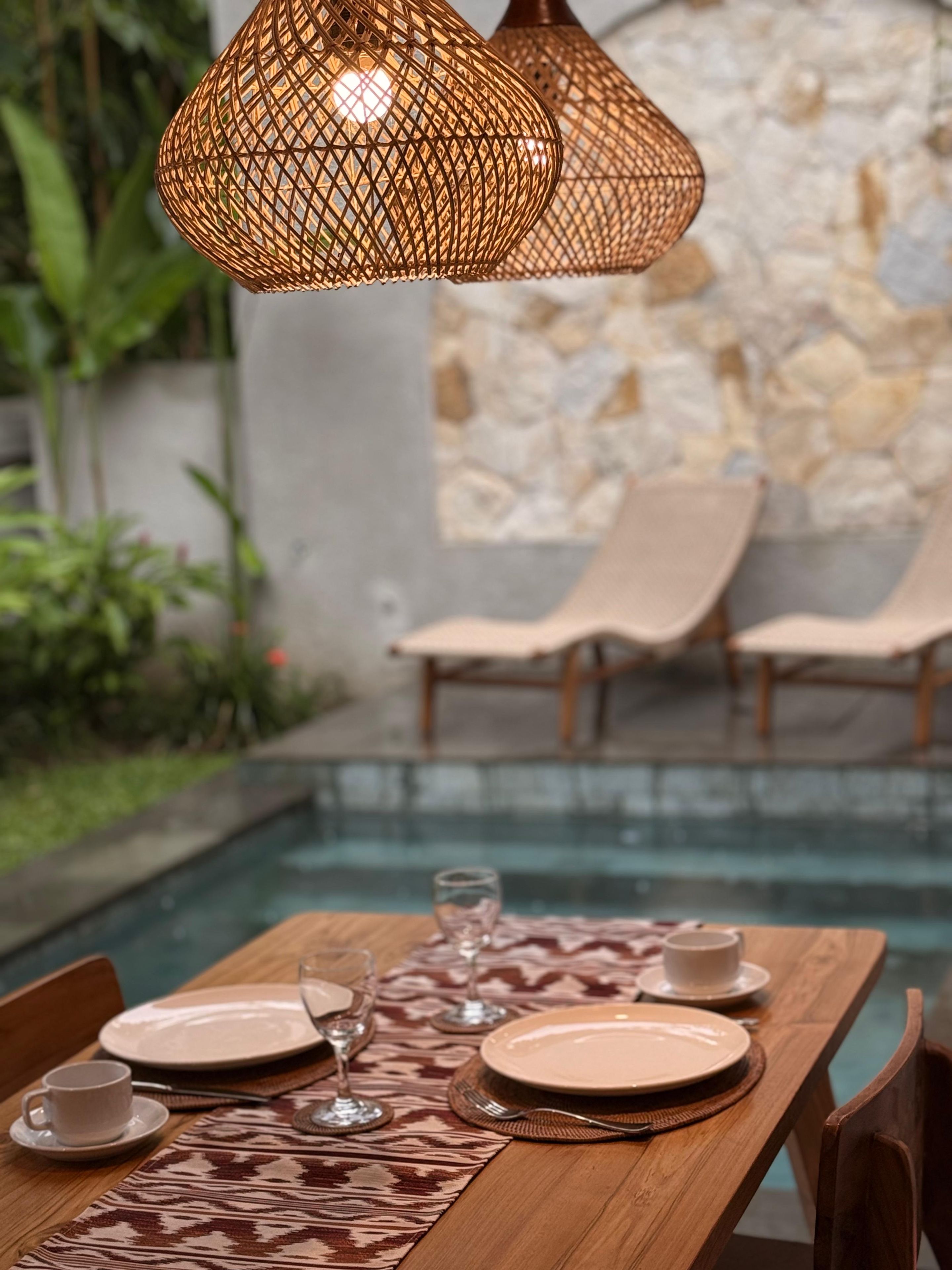 Una mesa de comedor dispuesta con platos, vasos y cubiertos, con un camino de mesa estampado.