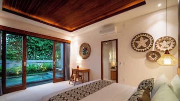 Un dormitorio con una cama grande, un escritorio y vistas a un jardín a través de puertas de vidrio.