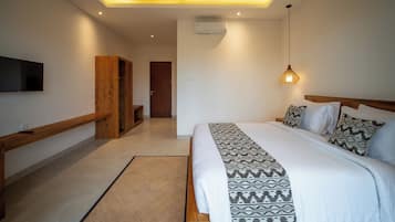 Un dormitorio moderno con una cama grande, un televisor montado en la pared, un banco de madera y una lámpara en el techo.