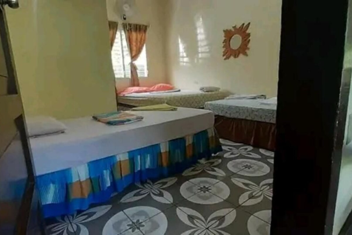 Una habitación pequeña con cama, escritorio y ventana con cortinas.