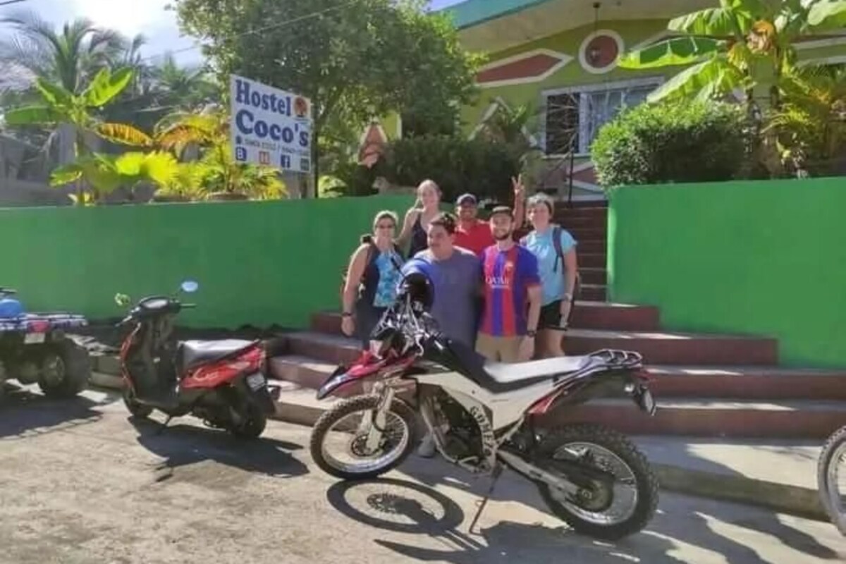 Un grupo de personas de pie frente a un edificio con un letrero que dice 'Hostel Coco's'.