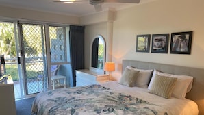 Habitación de hotel con una cama, un escritorio, una silla y vistas a través de un ventanal.