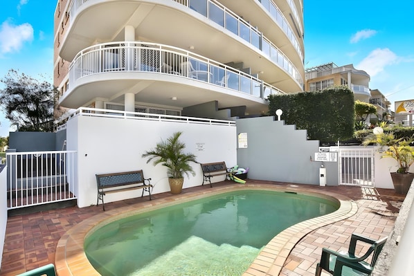A multi-level residential building with a swimming pool, outdoor seating, and a gated entrance. - Belvedere Apartments (Sunshine Coast)