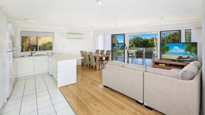 Un espacio habitable moderno con cocina, comedor y un amplio ventanal con vistas a la playa.