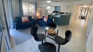 Una sala de estar moderna con un juego de sofá, una mesa de comedor con sillas, una zona de cocina y un ventilador de techo.