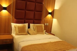 A hotel room with a large bed, two bedside tables, and wall-mounted lighting. - Clen Phil Hotels And Suites (Port Harcourt)