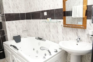 A modern bathroom with a white bathtub, a sink, and a mirror. - Clen Phil Hotels And Suites (Port Harcourt)