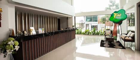 Un área de recepción moderna con un mostrador negro, un espacio de espera con sillas y vistas al exterior a través de amplias ventanas.