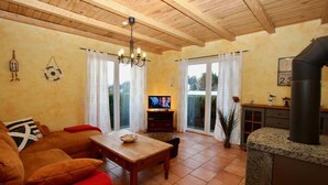 Una sala de estar acogedora con techo de madera, televisor, mesa de comedor y chimenea.