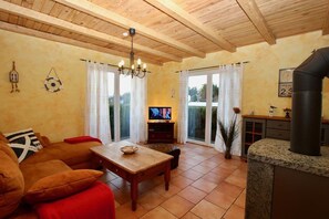 Uma sala de estar acolhedora com teto de madeira, televisão, mesa de jantar e lareira.