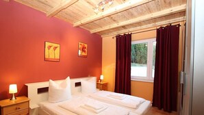 Un dormitorio con dos camas, techo de madera, una ventana con cortinas y una obra de arte en la pared.
