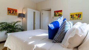 Une chambre à coucher avec un lit, des oreillers, une armoire et des œuvres d’art murales.