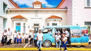 Un groupe de personnes se tient devant un bâtiment sur lequel est apposée une enseigne indiquant « EXPERT EN HÔTELLERIE ».