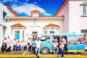 Um grupo de pessoas em frente a um edifício com uma placa que diz 'HOSPITALITY EXPERT'.