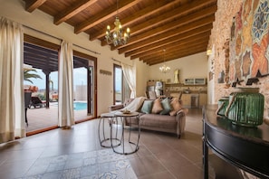 A spacious living area with a sofa, a coffee table, and a kitchen in the background. - Casa Rural La Morisca (Tuineje)