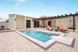 A swimming pool with a pergola and lounge chairs. - Casa Rural La Morisca (Tuineje)