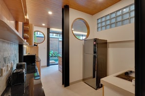 Eine moderne Küche mit einem Edelstahl-Kühlschrank, Holzschränken und einem großen Fenster mit Blick ins Freie.