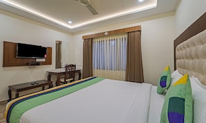 A hotel room with a bed, a desk, a chair, a television, and a window with curtains. - Treebo Trend Aaravi Residency (Puducherry)