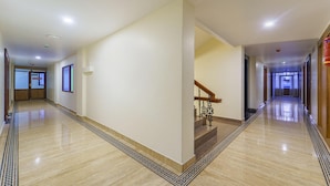 Corredor de hotel com piso de mármore, escada com corrimão de madeira e placa 'NO ADMISSION' em uma porta.