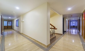 A hotel corridor with a marble floor, a staircase with a wooden handrail, and a 'NO ADMISSION' sign on a door. - Treebo Trend Aaravi Residency (Puducherry)
