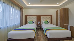 Quarto de hotel com duas camas, um guarda-roupa de madeira e uma mesa de cabeceira com telefone.