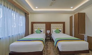 A hotel room with two beds, a wooden wardrobe, and a nightstand with a phone. - Treebo Trend Aaravi Residency (Puducherry)